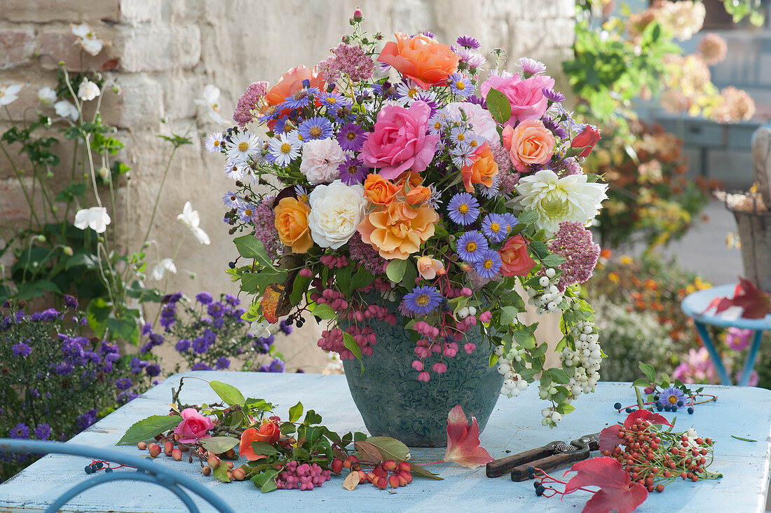 Colorful autumn bouquet of roses, asters, sedum plant, snowberries, dahlia and eu cone, branch with rose hips
