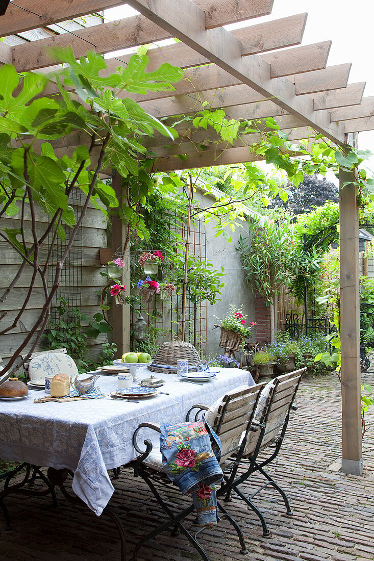 Gedeckter Tisch mit blau-weißem Geschirr auf Terrasse mit Sonnenschutz