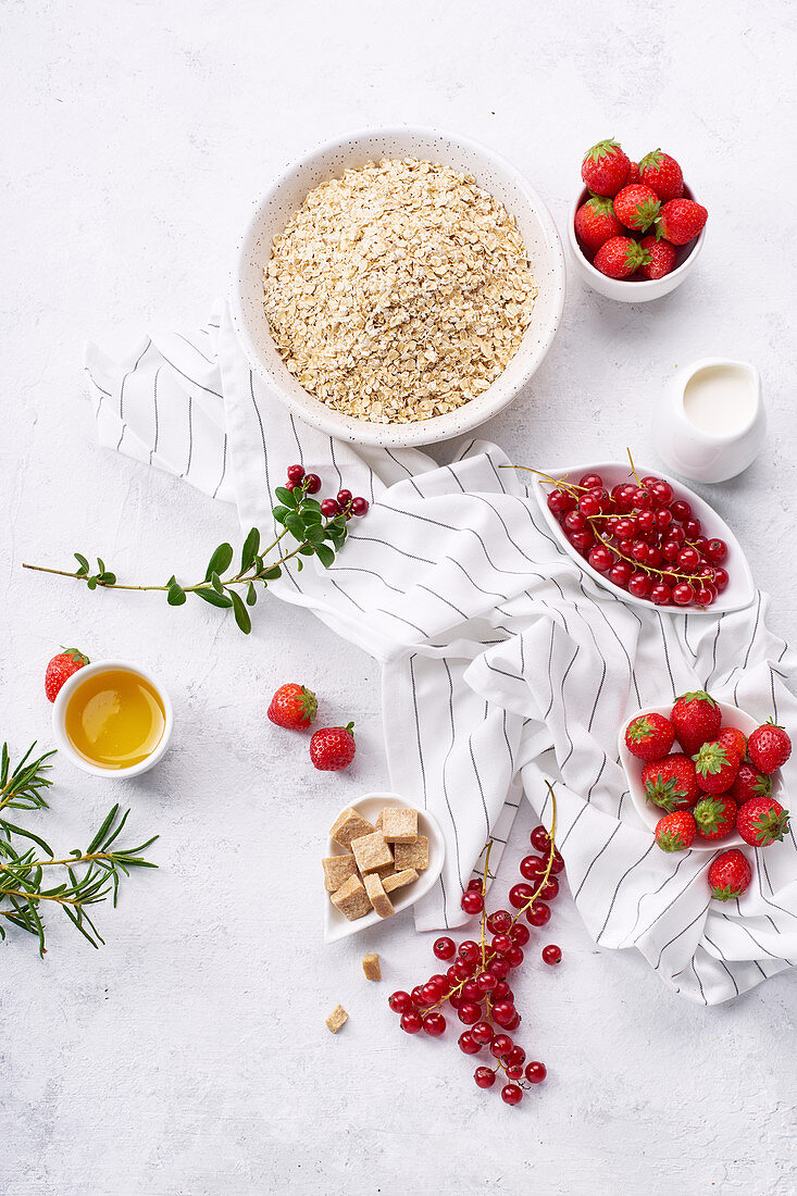Zutaten für gesundes Frühstück: Haferflocken, Erdbeeren und rote Johannisbeeren