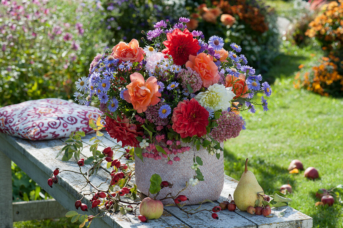 Bench with an autumn bouquet of dahlias, asters, roses, stonecrop, and spindle