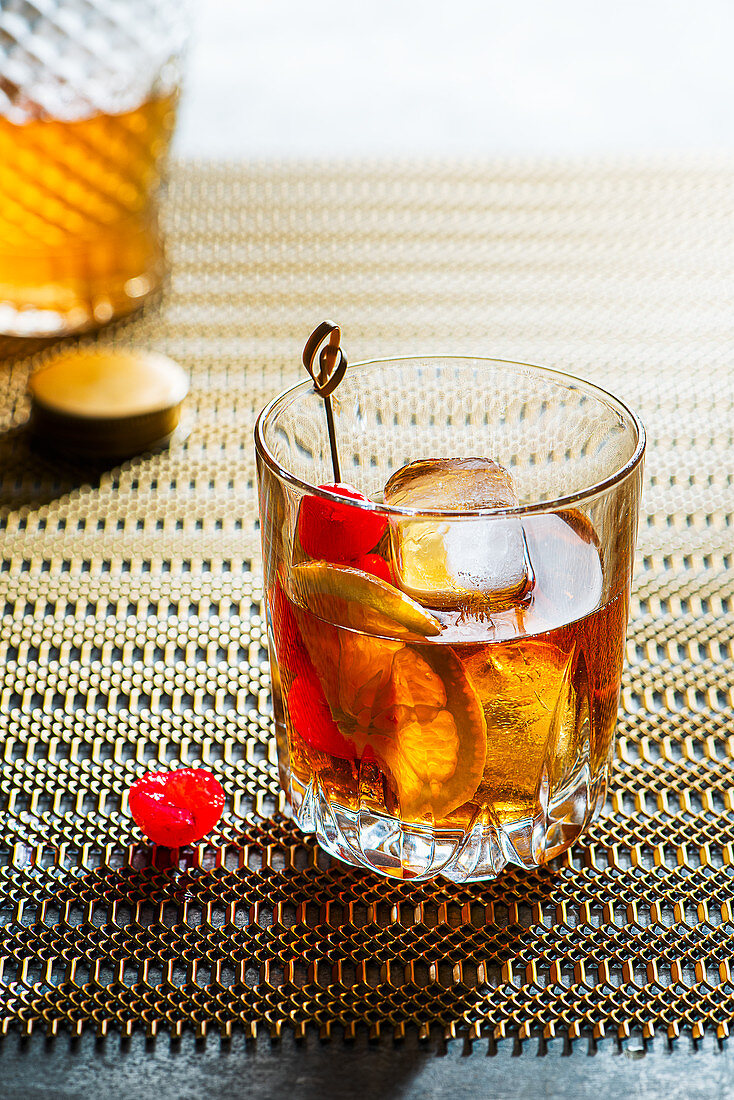 Old fashioned cocktail, whiskey on the rocks with bitters, orange and marashino cherry