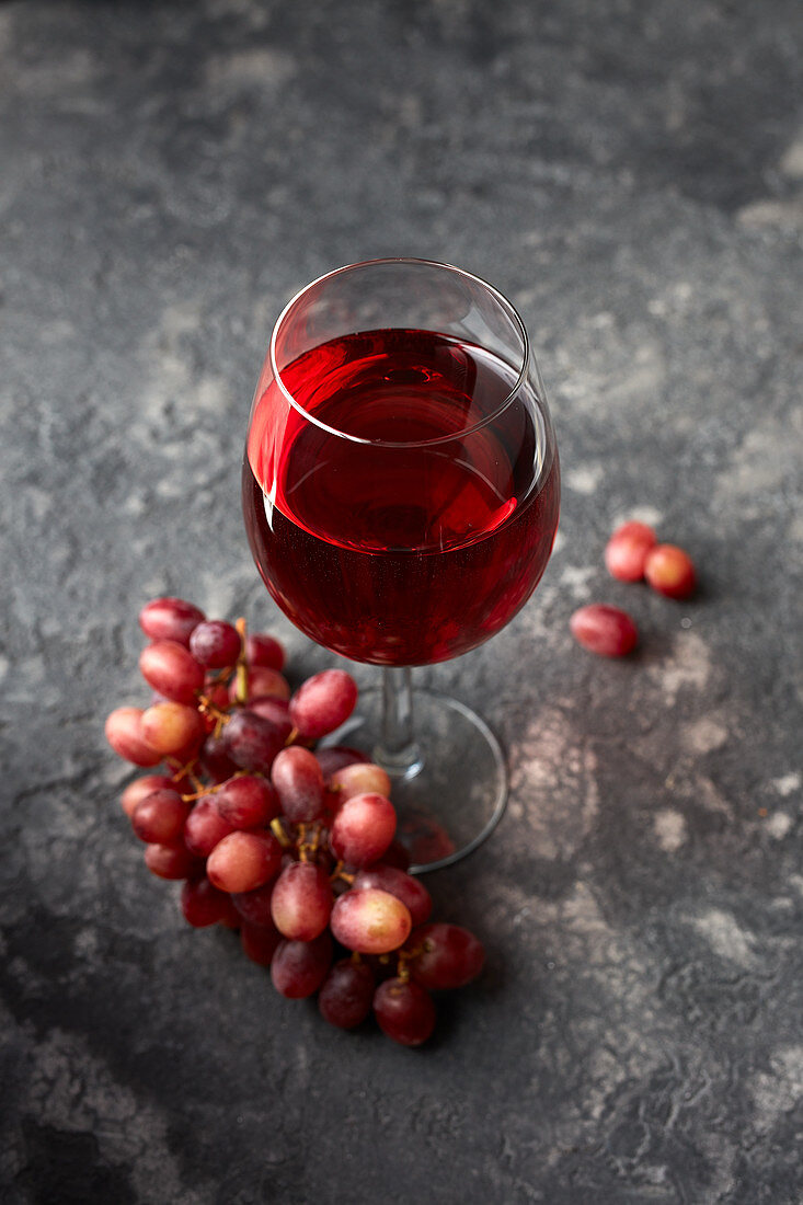 A glass of red wine with grapes