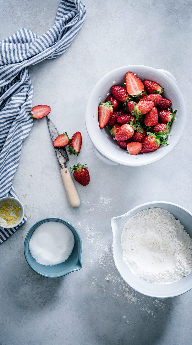 Backstilleben mit Erdbeeren, Mehl, Zucker und Zitronenschale