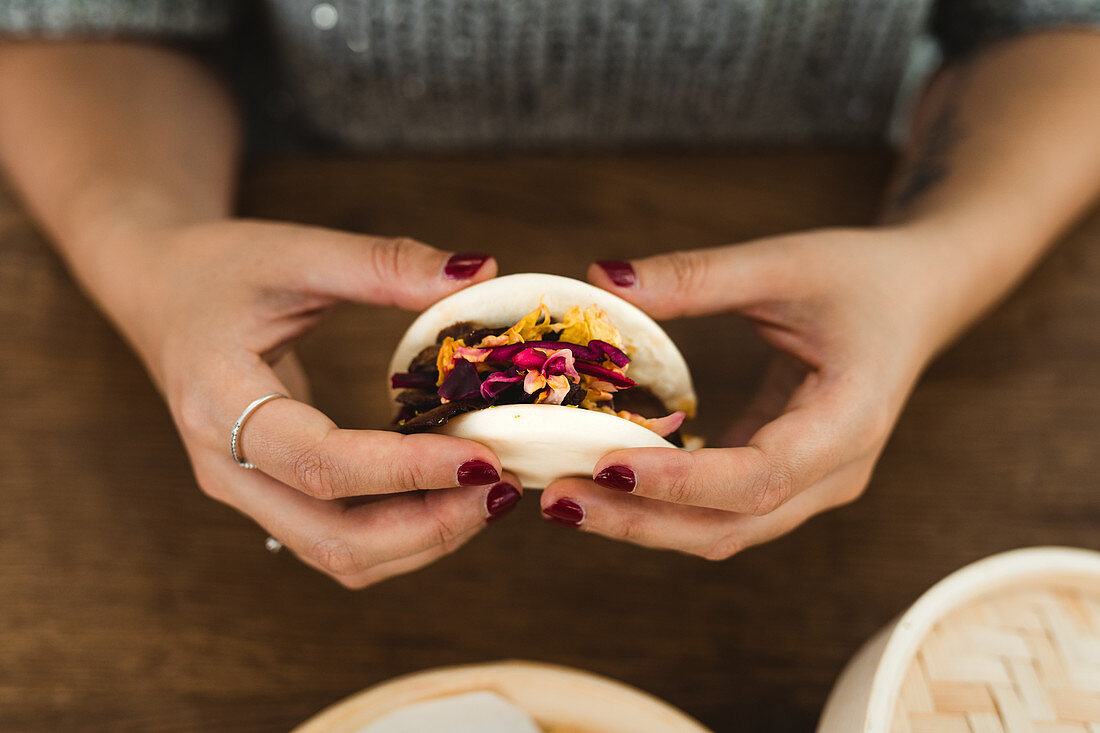 Frauenhände halten Bao Bun (gedämpftes Brötchen, Asien)