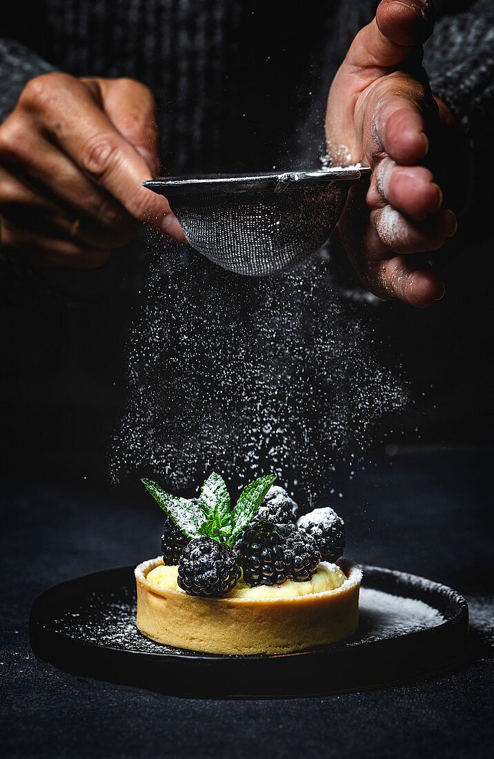 Person hands holding a homemade small cake with blackberry and delicious cream of vanilla and mint