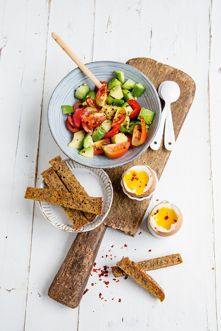 Breakfast eggs with avocado and tomato salad and bread sticks