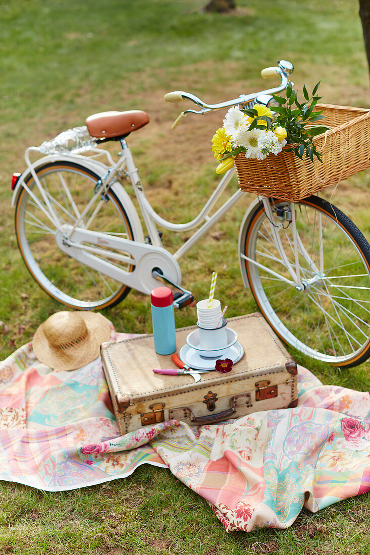 Fahrrad und Vintage-Picknickkoffer auf Decke