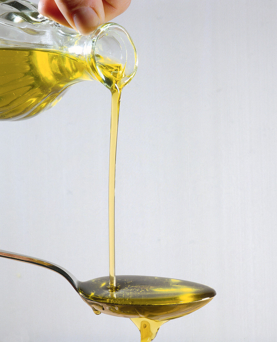 Olivenöl auf einen Löffel gießen