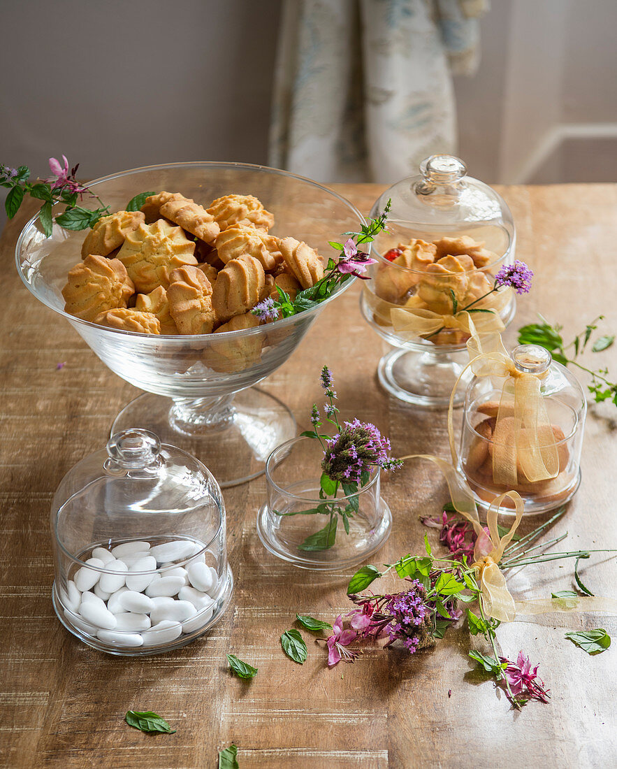 Biscuits and sugared almonds in glass jars bowls