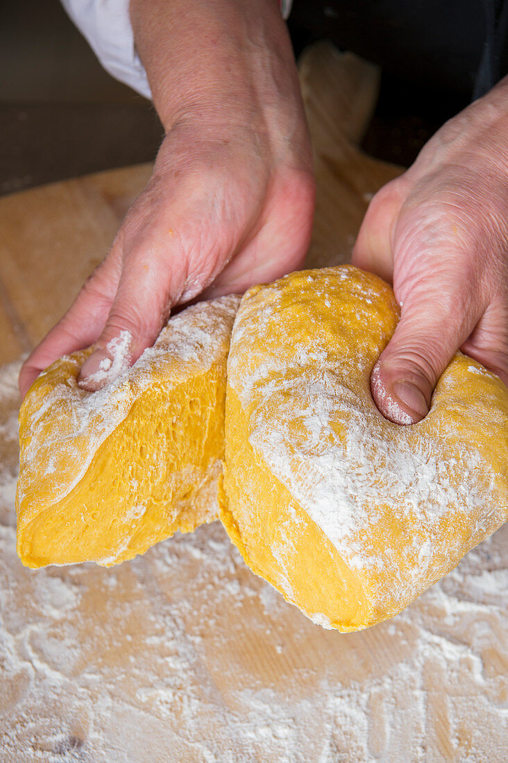 Hände teilen eine Kugel Nudelteig