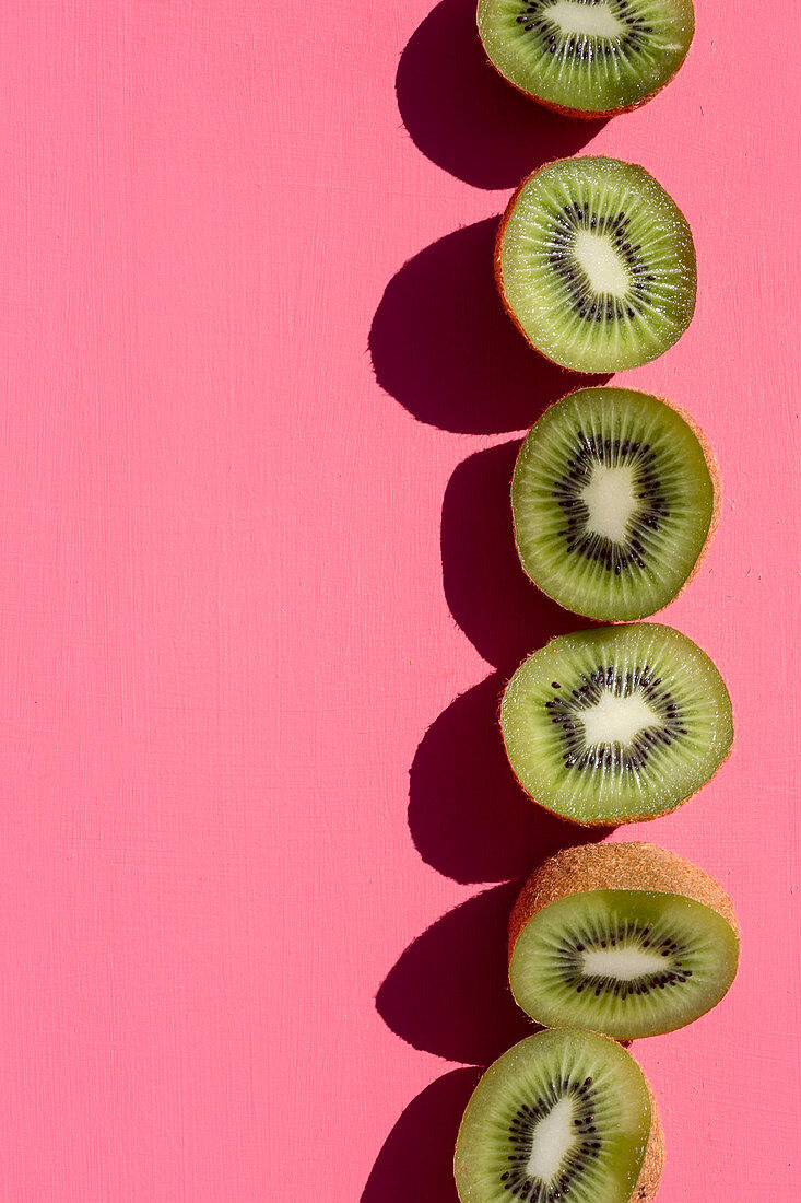 A row of kiwi halves on a pink background