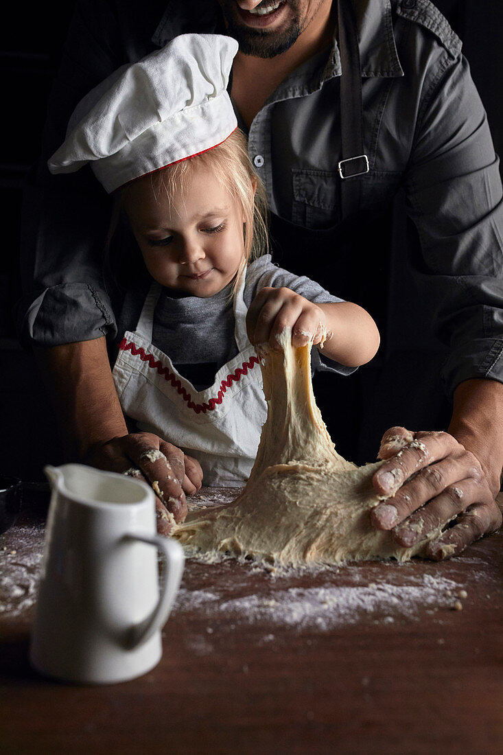 Father and daughter kneading the dough together
