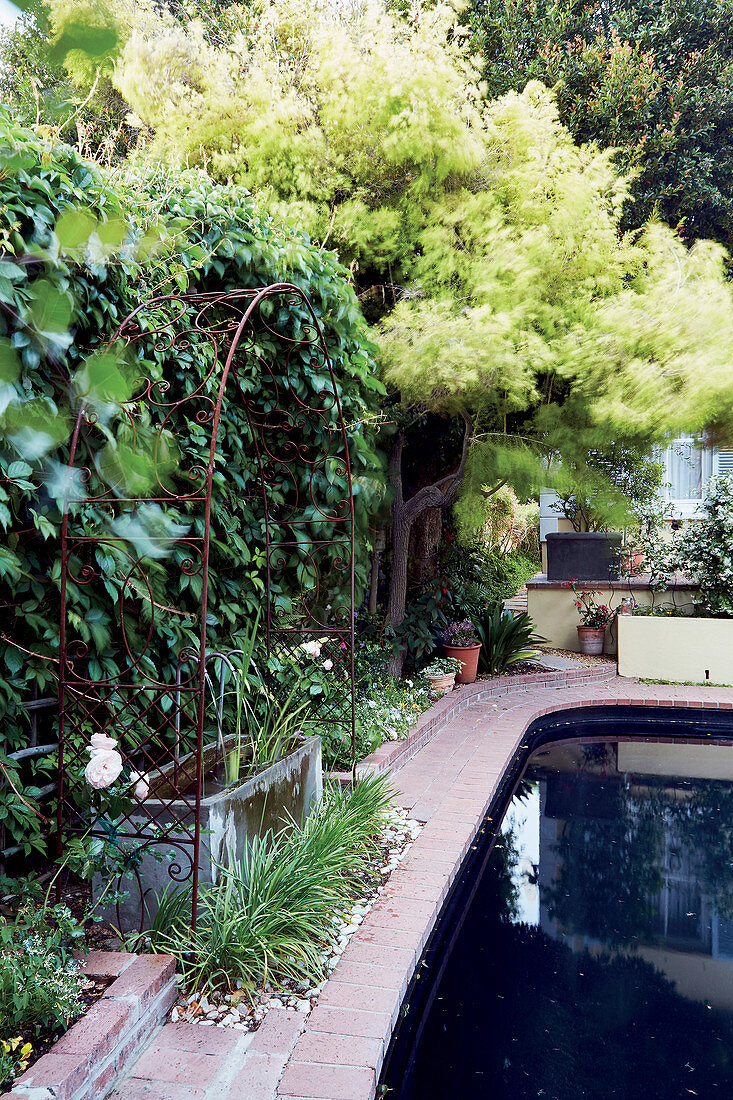 Wrought iron rose arch next to garden pond