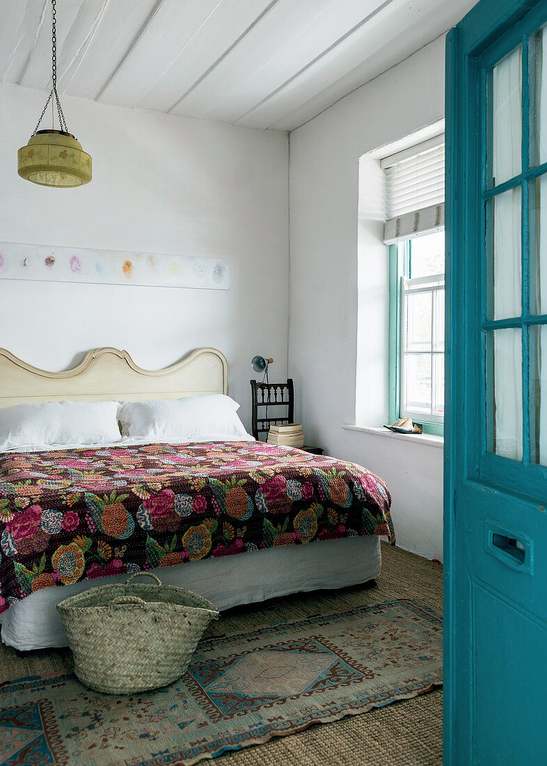 Open blue door leading into guest room with decorative handmade quilt on bed