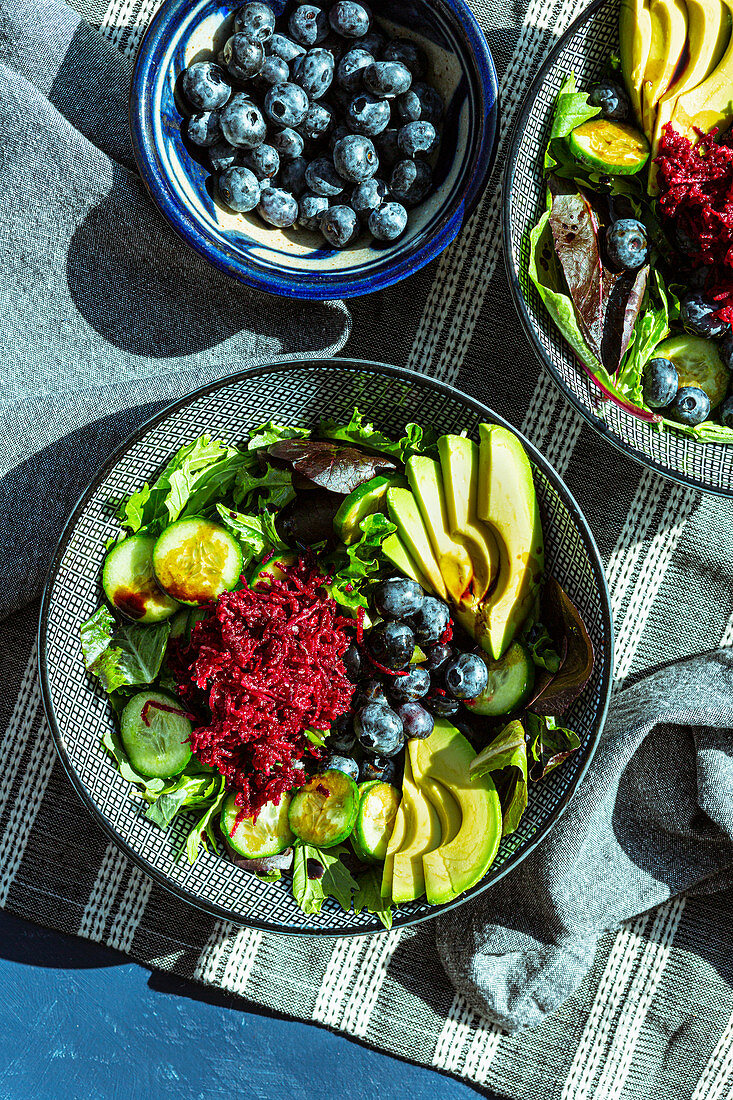 Salad bowls with avocado, beetroot, cucumber and blueberries