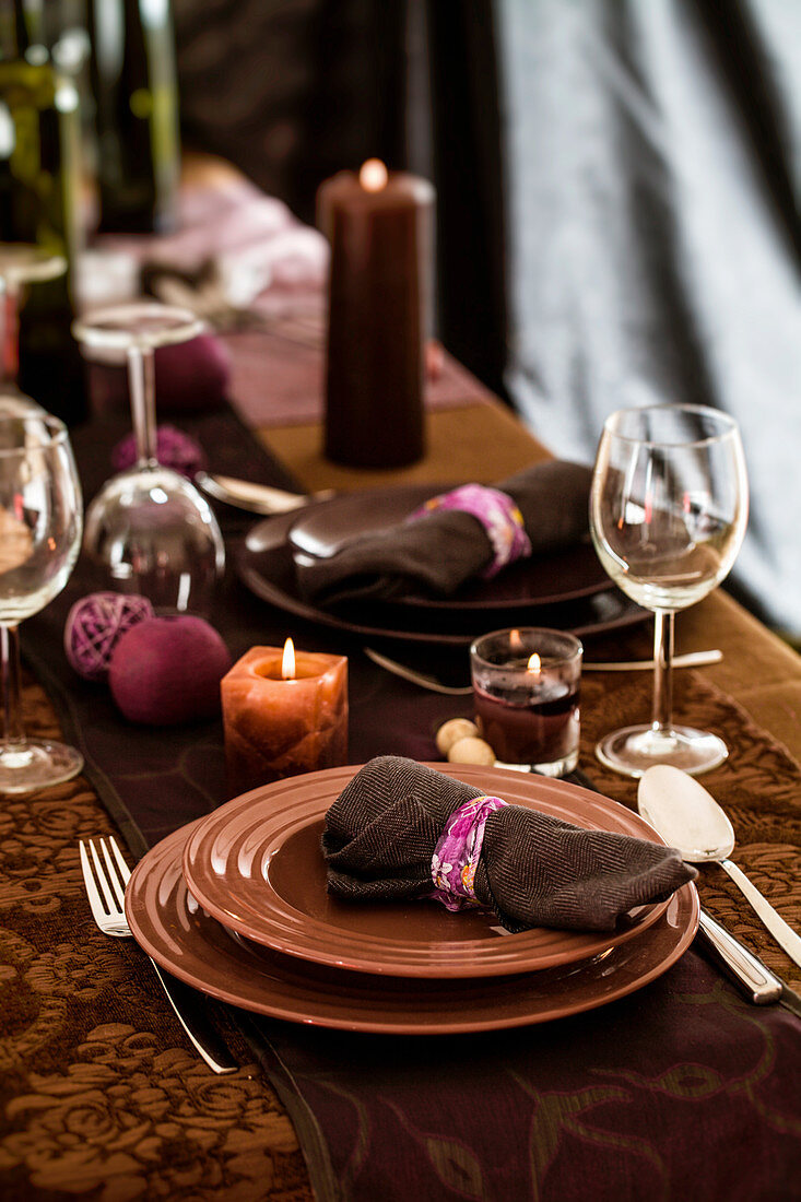 Elegant festlich gedeckter Tisch in Braun und Lila mit Tischläufer und Kerzen