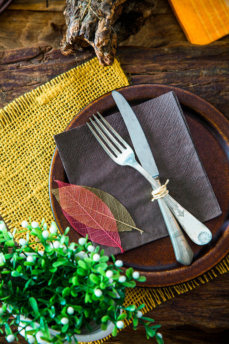 A rustic spring place setting decorated with leaves and green plants