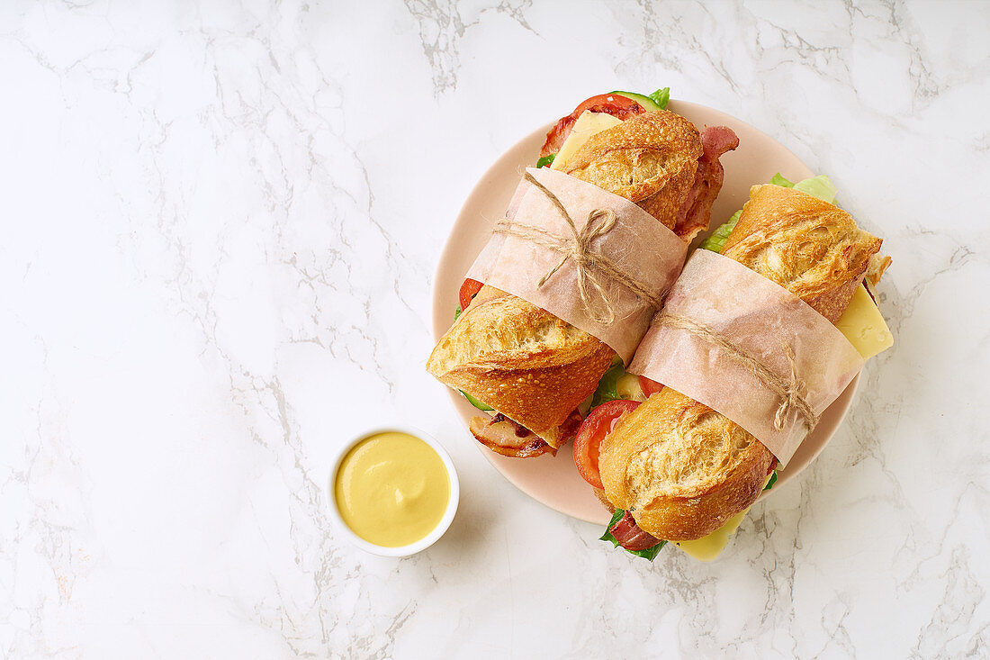 Fresh big baguette sandwiches with bacon, chedder cheese, mustard, lettuce and vegetables