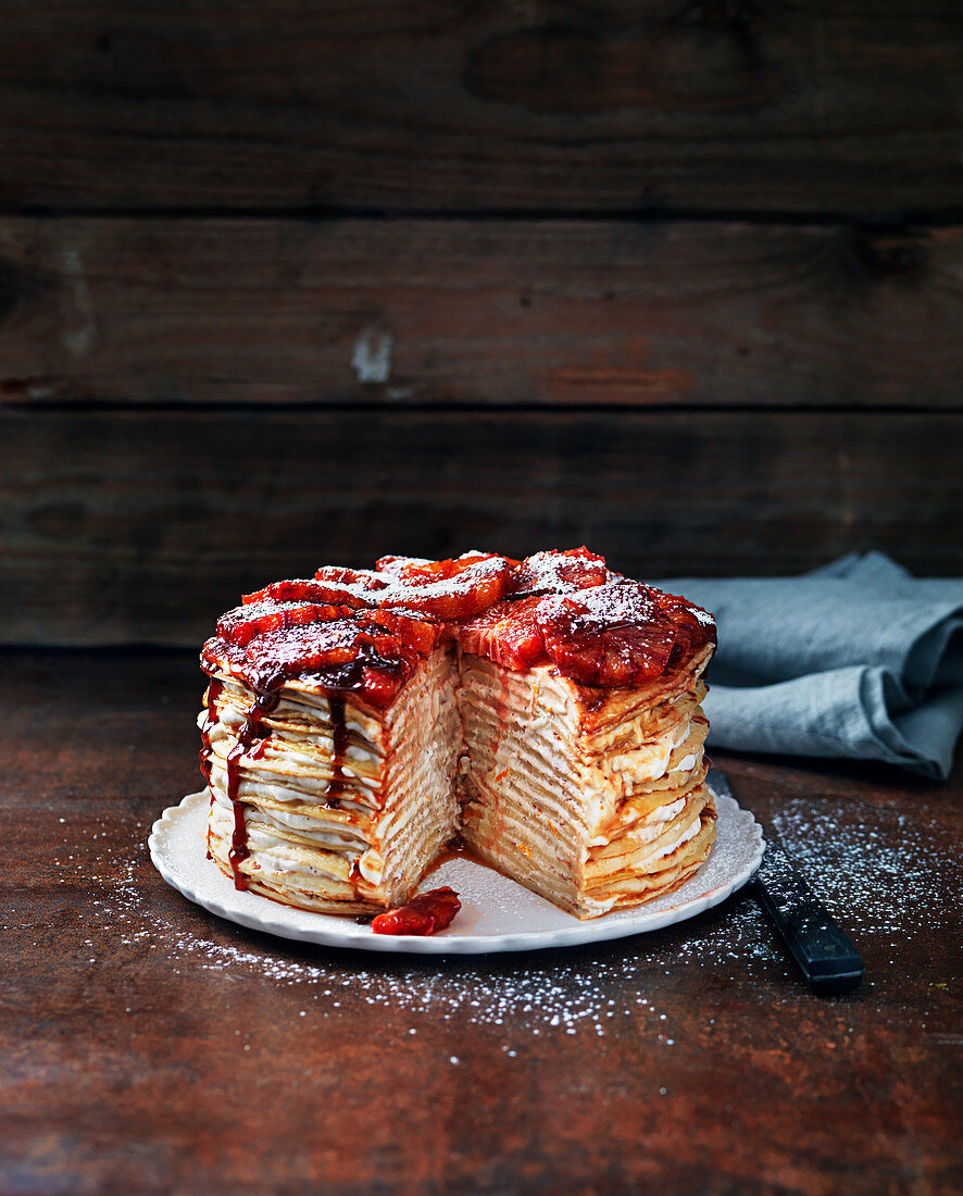 Pancake cake with jam, strawberries and icing sugar