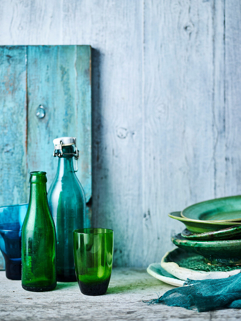 Stilleben mit grün-blauen Tellern, Gläsern und Flaschen