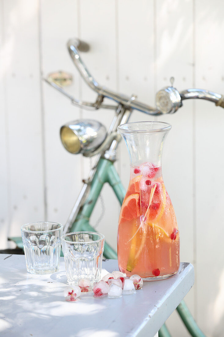 Summer lemonade with blossom ice cubes in a glass caraffe