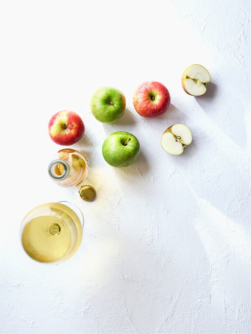 Cidre in Glas und Flasche, daneben frische Äpfel