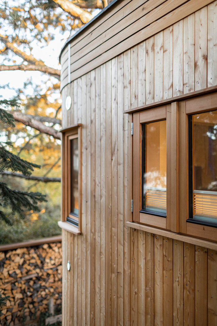 Round extension of tiny house with multiple small windows and wood-clad exterior