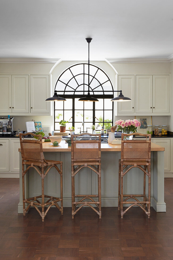 Black, metal, arched window and cane-backed barstools in kitchen