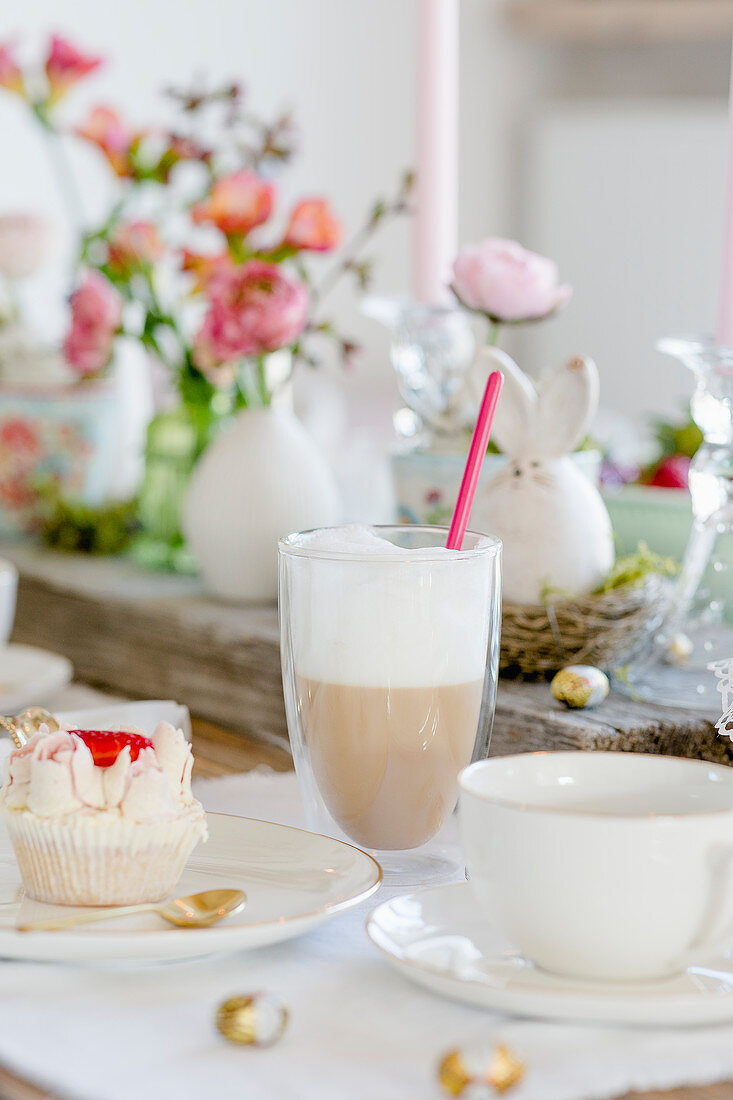 Latte macchiato and a cupcake on a table laid for Easter