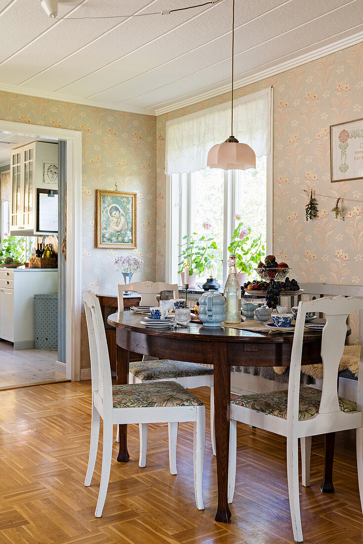 Round, antique table and country-house chairs in bright dining room