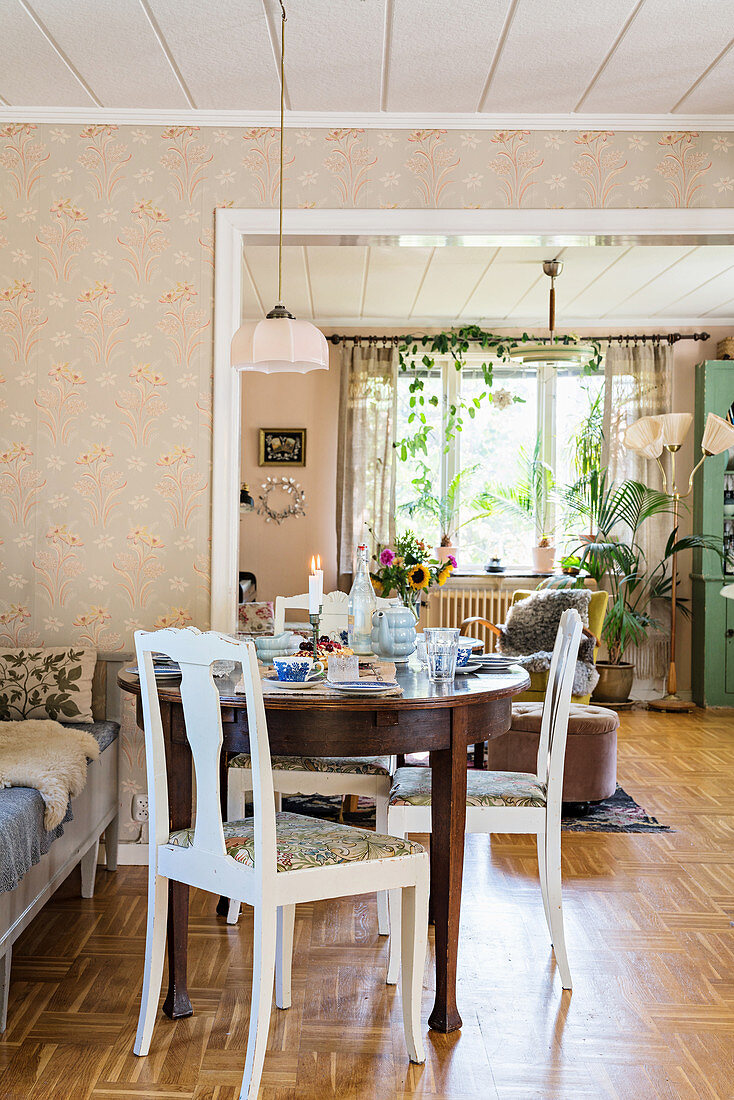 Round, antique table and country-house chairs in bright dining room