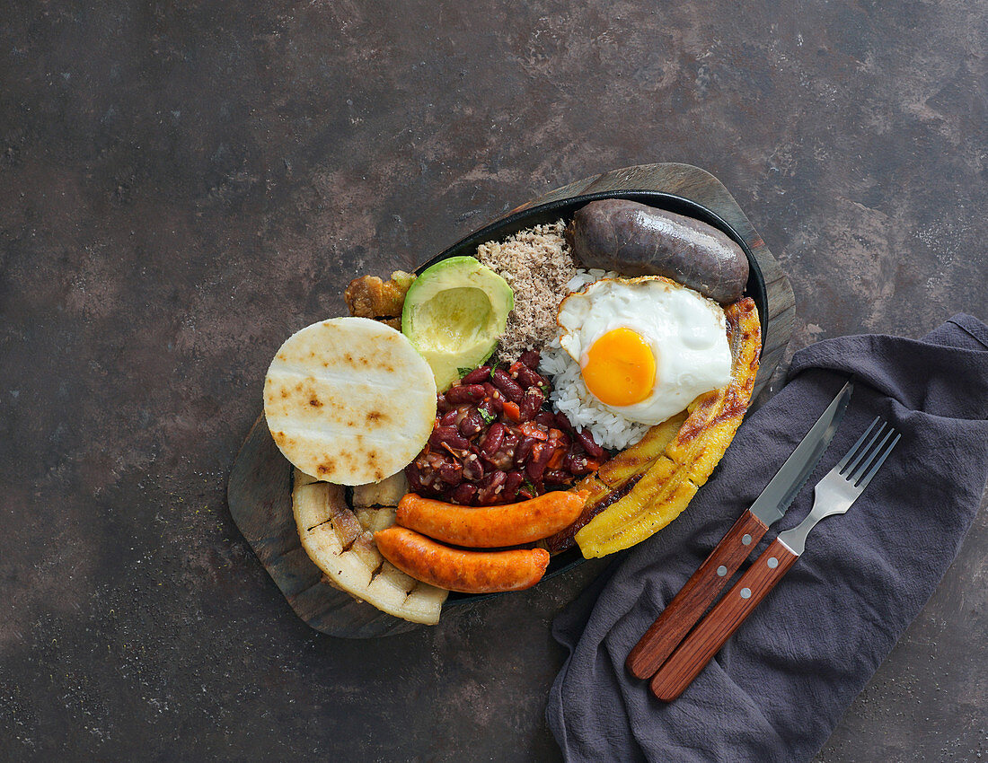 Bandeja paisa - gebratener Schweinebauch, Blutwurst, Wurst, Arepa, Bohnen, Kochbanane, Avocado, Ei und Reis (Kolumbien)