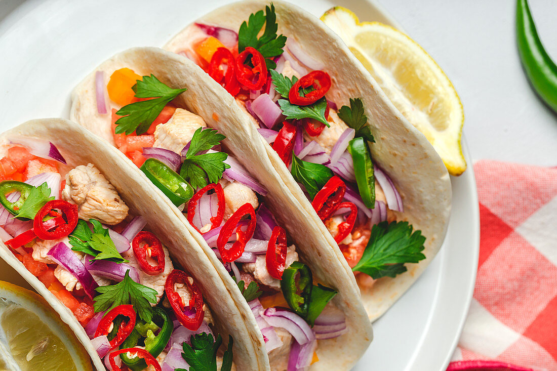 Homemade Mexican Tacos with fresh vegetables and chicken on white background