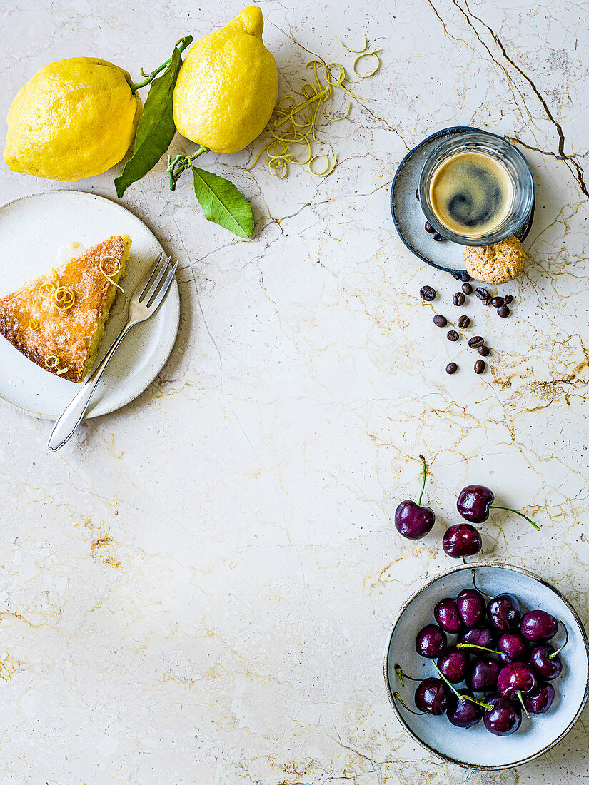 Ein Stück Zitronenkuchen, Zitronen, Espresso und Kirschen