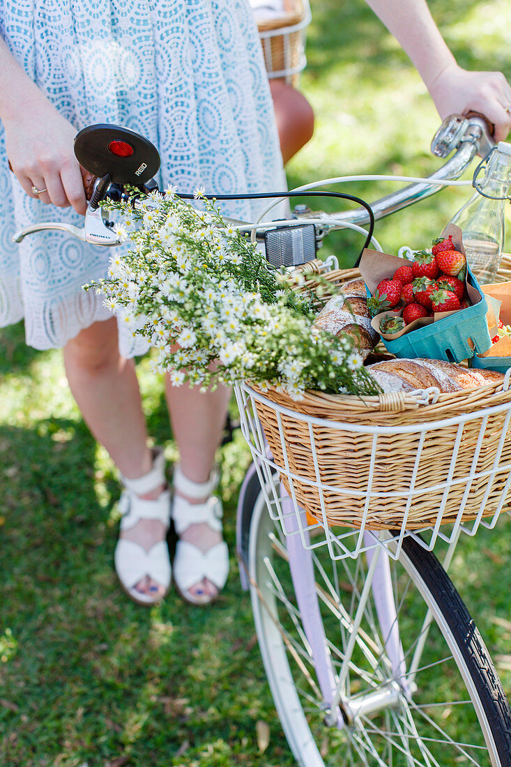 Frau hält Fahrrad mit Picknickkorb