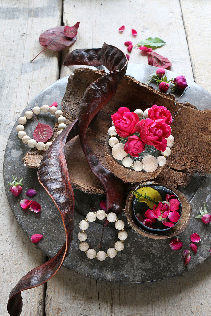 Herbstarrangement aus Baumrinde, Rosenblüten, Holzperlen und Johannisbrotbaumschote