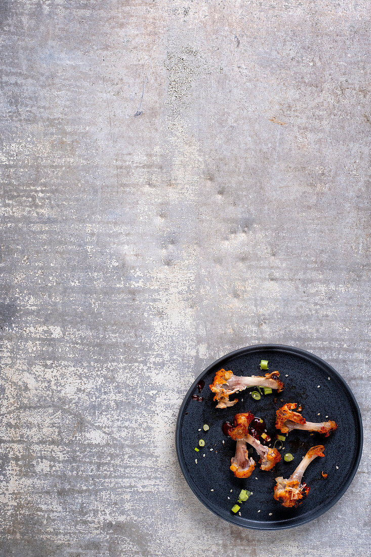 Plate with the left overs of eaten chicken wings, barbecue sauce and spring onions