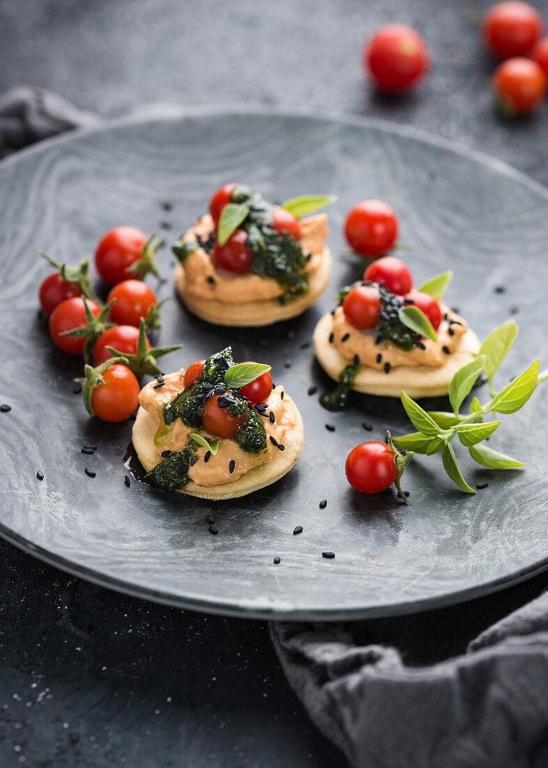 Herzhafte Mürbeteigplätzchen mit Chili-Hummus, Cocktail-Tomaten und Basilikum-Pesto. Vegan.