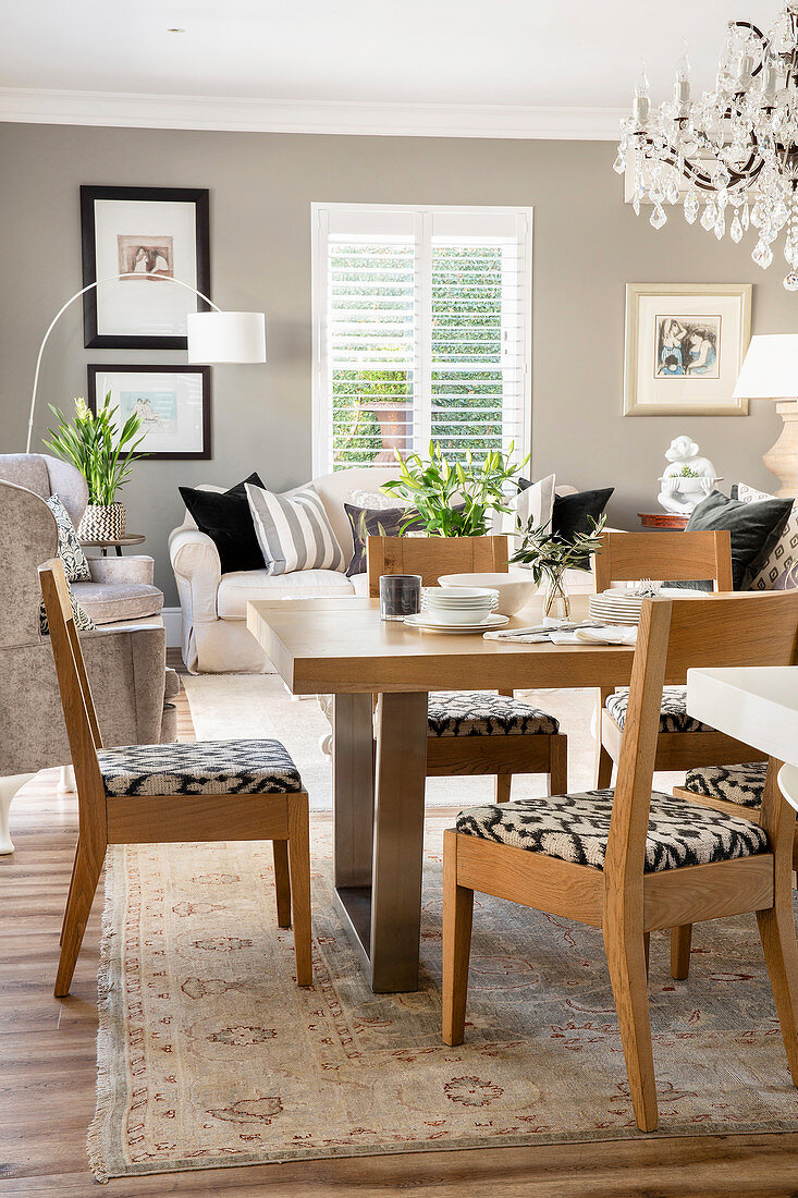 Wooden dining set in open-plan interior with grey wall