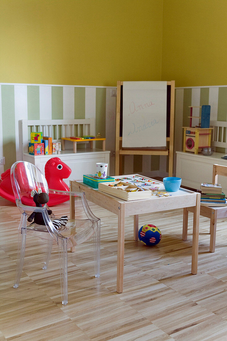 Wooden chair and Ghost chair at drawing table in play area of children's bedroom