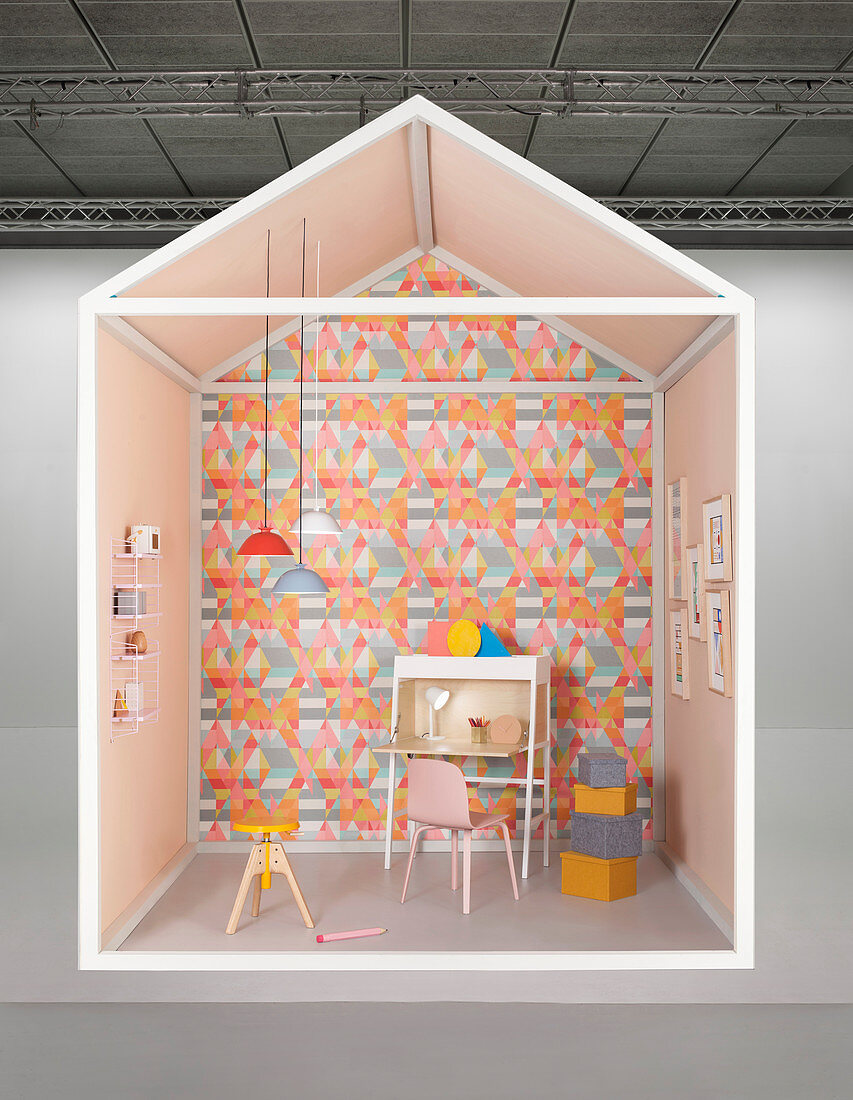 Creative design for study area with desk against wall covered in geometric wallpaper
