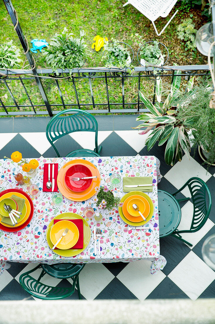 Terrace table set with floral tablecloth and brightly coloured place settings