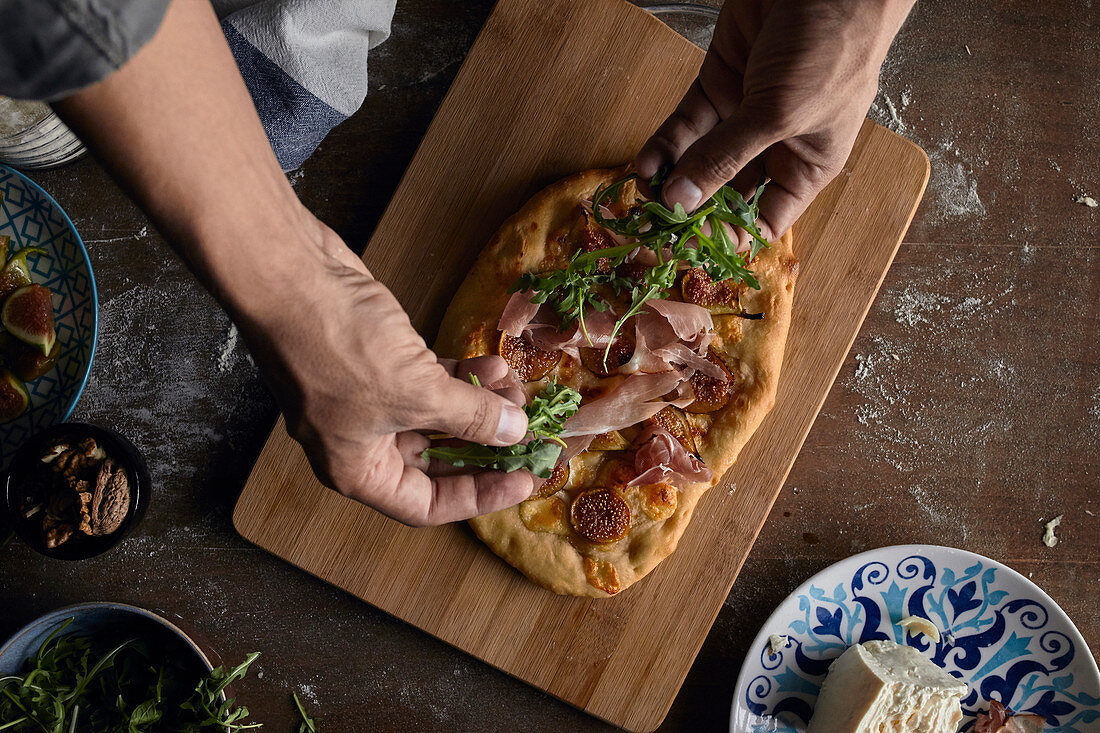 Frisch gebackene rustikale Pizza mit Rucola belegen