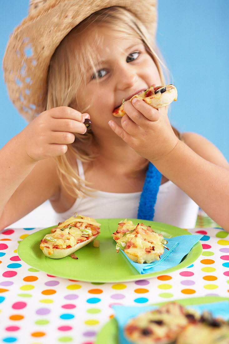 Kleines Mädchen isst Minipizza