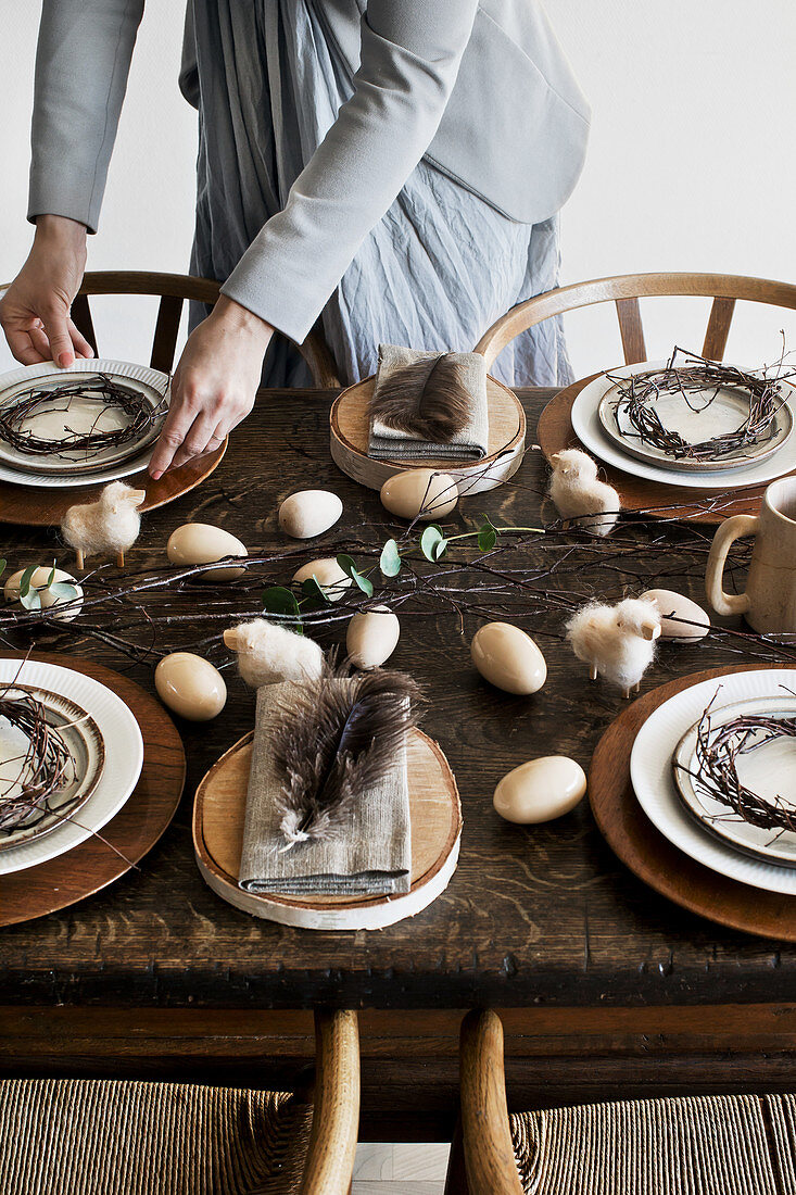 Woman setting old wooden table with rustic natural decorations