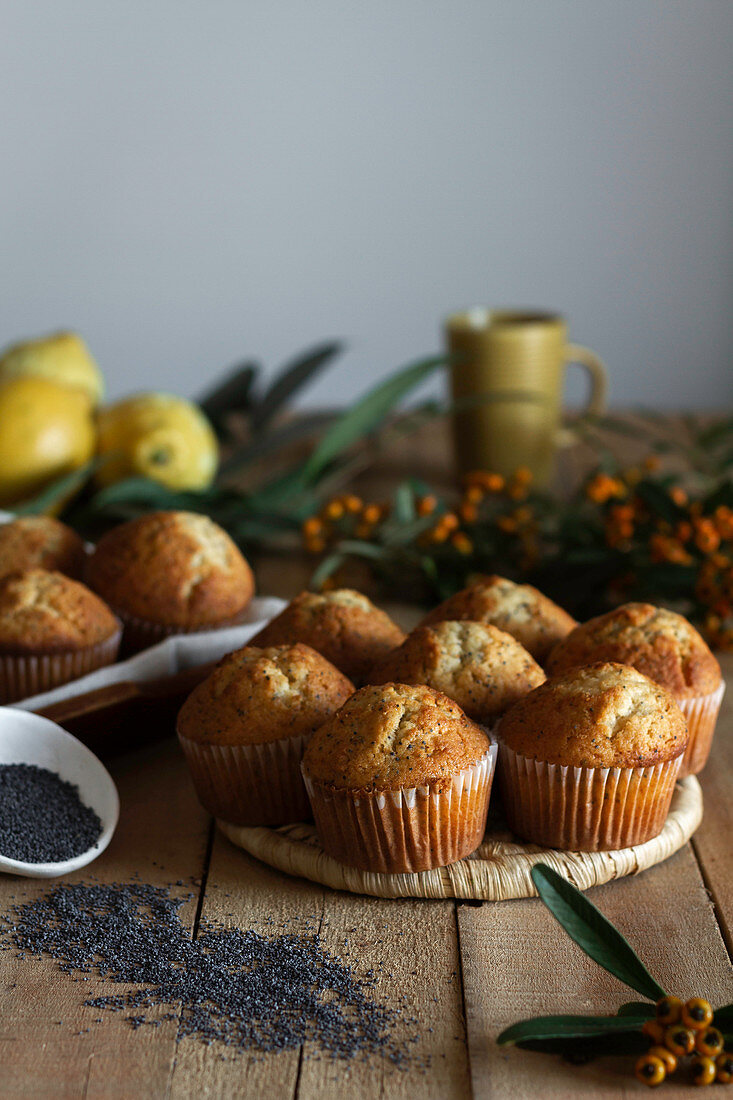 Cupcakes on wicker stand on wooden table decorated with berries lemon and poppy seed