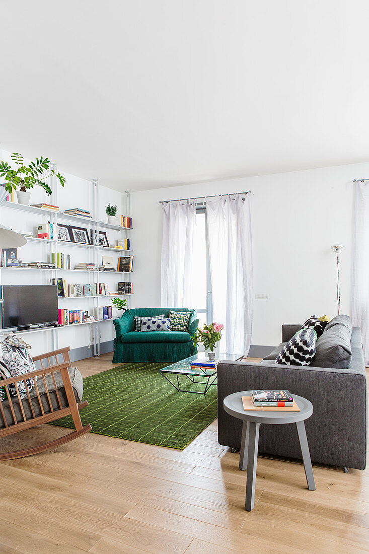 Grey sofa, rocking chair and green vintage-style armchair in seating area around TV