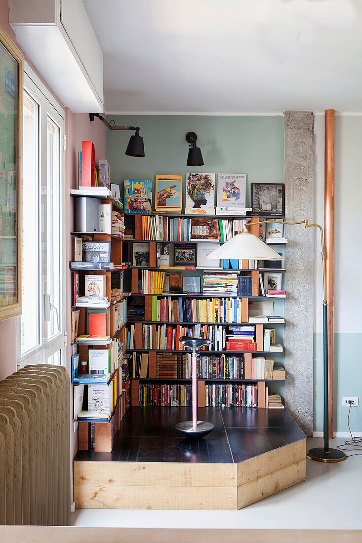 Bookcase made from bricks and metal shelves on platform in corner of room