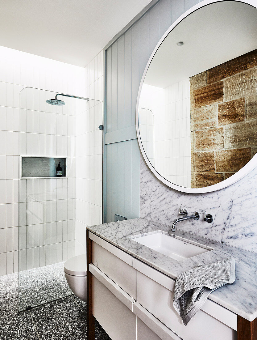 Round mirror above vanity with marble top in bathroom