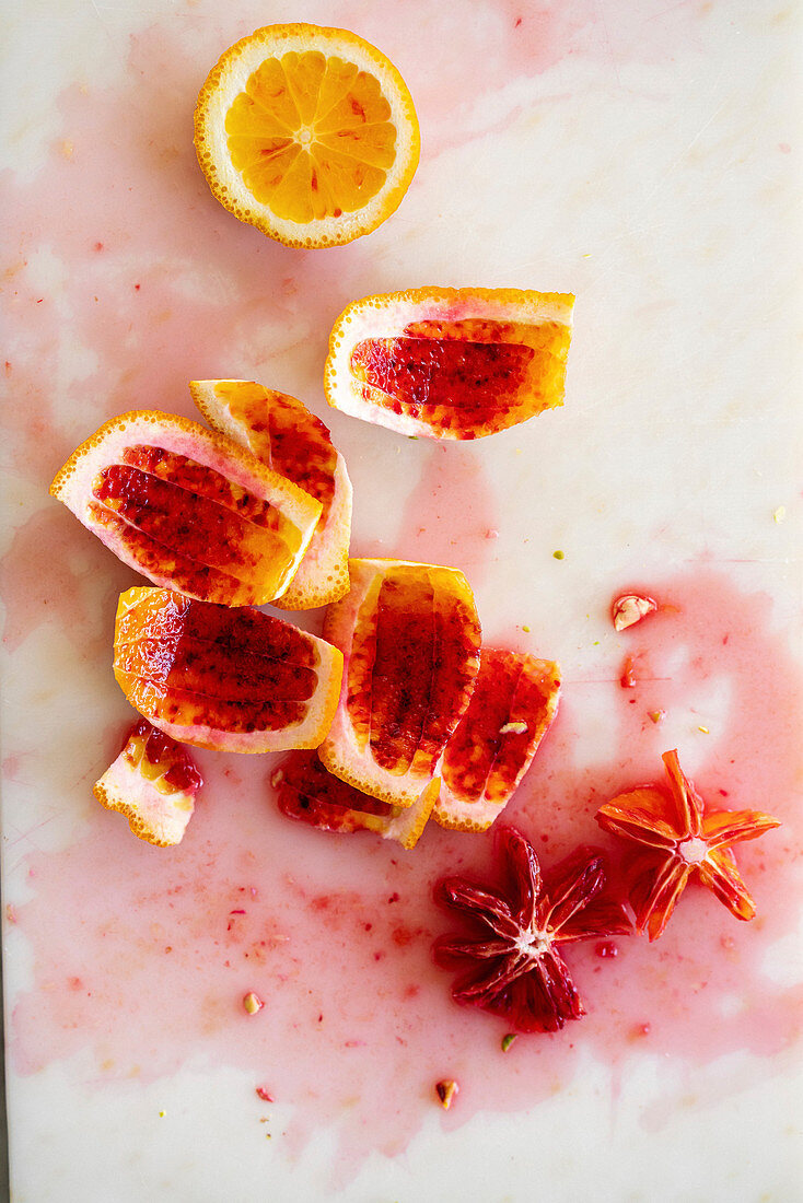 Blutorangen-Stilleben mit Orangenschalen und ausgeschnittenen Orangenblüten